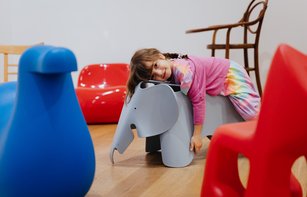 Ein Kind liegt auf einem Kinderstuhl, der wie ein Elefant aussieht.