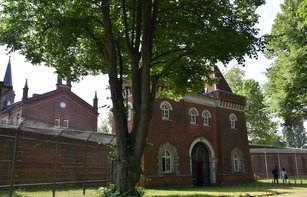 Torhaus hinter Bäumen aus rotem Klinker